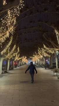 Calatayud, Spain,12/30/2024: Man walking under christmas lights in Salou
