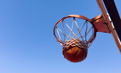 Basketball scoring a basket as it goes through the hoop and making a swish in the net