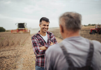 Farmer in soybean field talking to other man during harvest