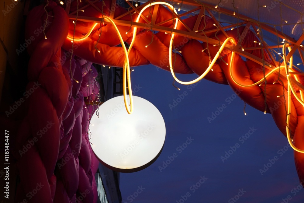 Poster round white banner hanging against the background of an arch illuminated by zigzag garlands against 