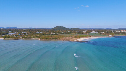 A drone shot of the beautiful emerald sea and clear green waves at Pyoseon Beach in Jeju Island, Korea