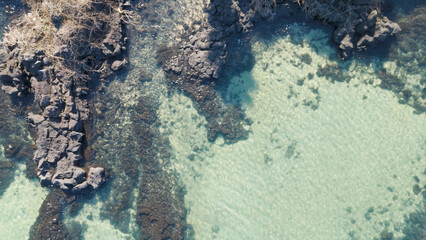A drone shot of the beautiful emerald sea and clear green waves at Pyoseon Beach in Jeju Island, Korea
