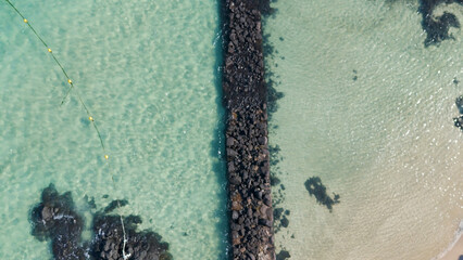 A drone shot of the beautiful emerald sea and clear green waves at Pyoseon Beach in Jeju Island, Korea