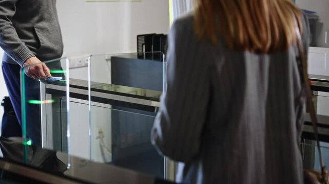 Passing through a turnstile into an office building. Office workers enter and exit through a modern turnstile, using a key card to enter.