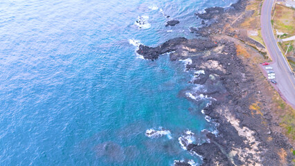 A drone shot of the beautiful sea scenery of Jeju Island, Korea, which boasts a green emerald cleanliness. Best healing trip. Harmony of basalt and waves