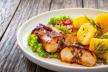 Baked rabbit saddle and boiled potatoes on wooden table