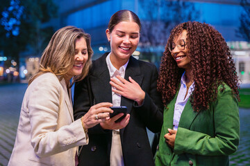 Businesswomen reviewing a smartphone outdoors at night