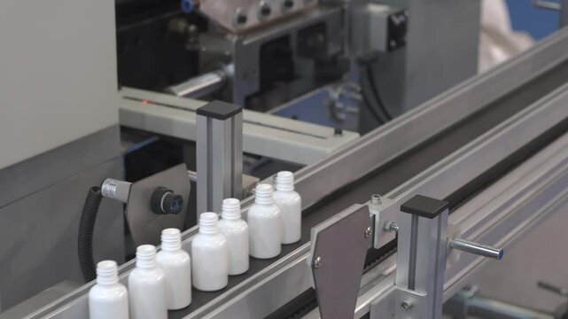 pharmaceutical industry, medicine pills are filling in the  bottle on production line machine conveyor at the medical factory. selective focus.