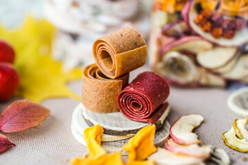 Freshly rolled, homemade fruit leather and dried fruit slices made from organic ingredients are displayed on a rustic table