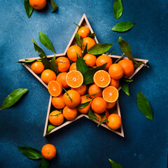 A box in the shape of a star with fresh tangerines. Green tangerine leaves. Free space for text. On...