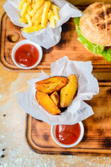 Close-up of home made tasty burgers and Fried Potatoes on wooden table.