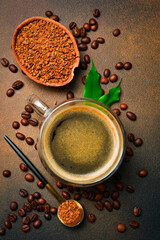A cup of brewed instant coffee and coffee beans in the decor. Top view.