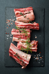 Raw sliced veal short spare loin ribs on a marble board. Black background. Top view. Copy space