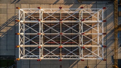 Fototapeta premium An aerial view of preassembled overhead supports stacked in an organized manner on scaffolding. The contrasting lines and shapes form an abstract pattern that speaks to the