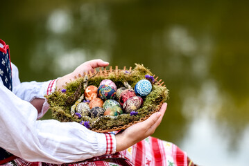 Woman in traditional Lithuanian clothes holding basket filled with Easter eggs