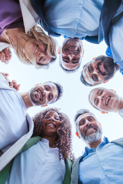 Group of businesspeople smiling in a huddle outdoors.Vertical