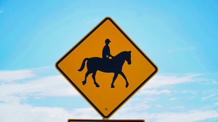 Caution horse riders sign under a clear blue sky in a rural area