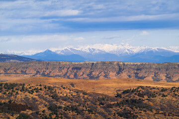 Naklejka premium Panorama of a wide mountain valley with a view of high mountains with glaciers and a cloudy sky