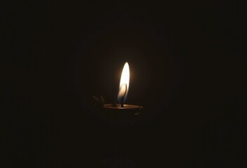 Flickering black candle in the dark, casting a soft, warm glow that enhances the shadows and creates a mysterious ambiance.