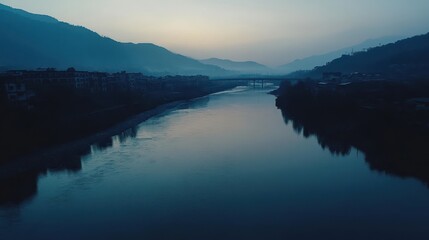 Fototapeta premium Serene Dawn over Mountain River Breathtaking Landscape Photography of a Calm River Reflecting Misty Mountains and a Quiet Village at Sunrise.