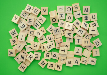 English alphabets wooden lettered tiles on green background. creating a playful and creative atmosphere. Ideal for concepts of language, education, and design inspiration.