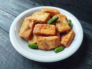 Goreng tempe or Fried tempeh on plate on wooden table. High angle view. Indonesian culinary 