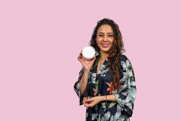 Beautician showing moisturizing cream on pink background