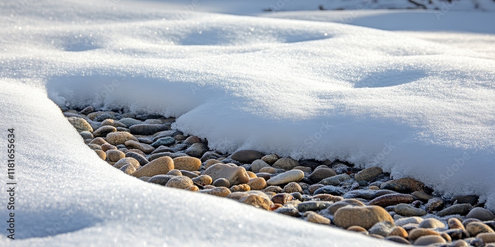 Aufkleber Snow flows gracefully over a mound of crushed pebbles, creating a beautiful contrast between the soft snow and the rugged surface of the crushed pebbles. The snow flows enhance the scene s aesthetics.