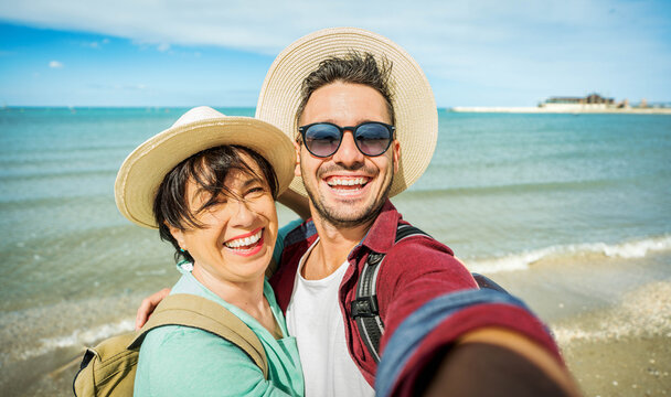 Happy mother and son taking selfie with smart mobile phone outside - Delightful family having fun at the beach - People and technology concept