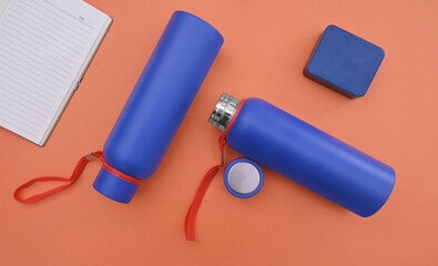 Blue water bottles and a small container on an orange background
