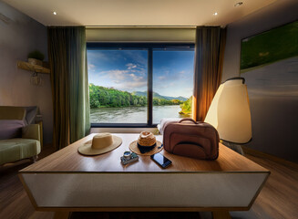 Serene river view from a luxurious hotel room.  Sunlight streams in, illuminating a table with travel essentials: hats, bag, phone.  Relaxing getaway.
