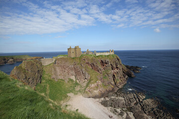 Dunnottar Castle perched on rugged cliffs overlooking the North Sea in Stonehaven, Scotland under a...