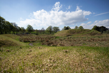 Obraz premium Explore the ancient earthworks in Scotland under a bright blue sky and scattered clouds during a tranquil afternoon