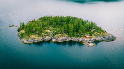 Aerial view of a green island with a red cabin.