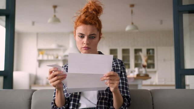 Caucasian woman serious homeowner girl female at home couch reading letter paper notification debt trouble check payments bills analyze expenses budget money finances loan credit bank mortgage problem