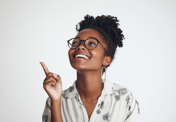 Portrait of a happy young woman wearing glasses, smiling and pointing her finger upward, isolated on a white background. 