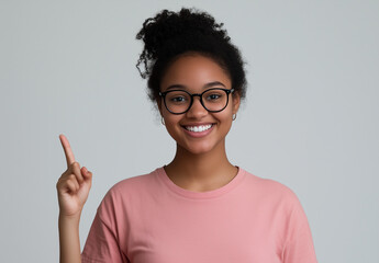 Portrait of a happy young woman wearing glasses, smiling and pointing her finger upward, isolated on a white background. 