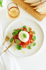 Salad Caprese with tomato, cherry, mozzarella and basil leaves on white wooden table