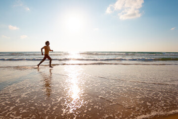 man runs along the sandy beach. fitness training on a sunny summer day. running on the beach.