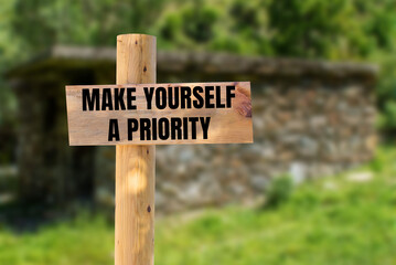 Make yourself a priority message written on wooden sign with blurry nature background. Conceptual make yourself a priority symbol. Copy space.