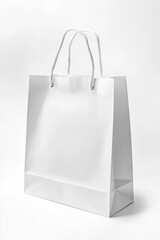A plain white shopping bag with sturdy handles stands upright on a light surface. It is ideal for retail use or as a minimalist gift packaging solution.