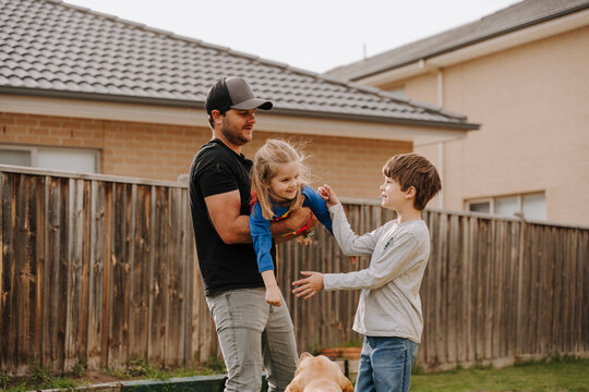 Dad simulating a flight for daughter in superhero costume.