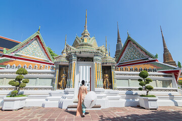 Young asian woman wearing traditional Thai dress at the Wat Pho Temple, a popular destination for...