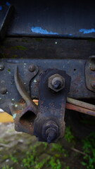 Close-up view of a weathered metal structure with rust, bolts, and moss growth, showcasing the effects of aging and exposure to the elements 