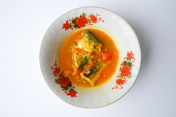 Fresh fish soup in a simple basin, served with spices and sliced chili