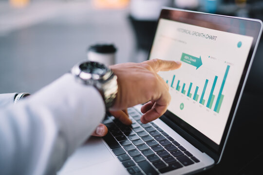 Cropped image of male professional checking financial website with revenue statistics pointing on marketing infographics, expert man browsing web page with graph charts of corporate monetary gain