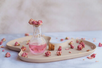 Rose  essential oil in glass bottle and pink rose flowers 