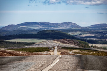 Scenic view of a winding road through the Scottish Highlands under a clear sky