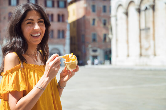 Fototapeta Beautiful smiling woman eating traditional italian ice cream on the street in Italy 