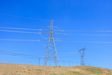 High voltage power tower under blue sky. Industrial background.